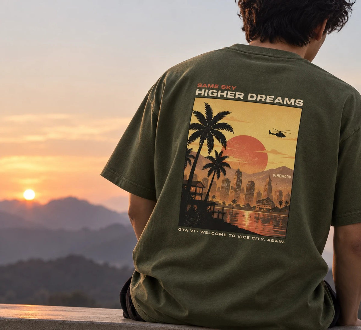 Person in an olive Oddsaint tee with a sunset poster back print
